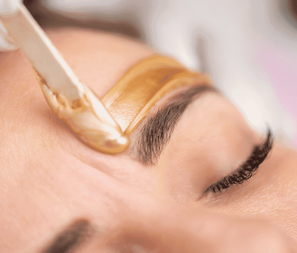 Eyebrows being shaped with warm wax for grooming and precision.